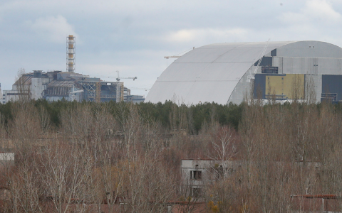 Заброшенные дома работников Чернобыльской АЭС в Припяти на фоне строящейся арки над разрушенным реактором, 23 марта 2016 года